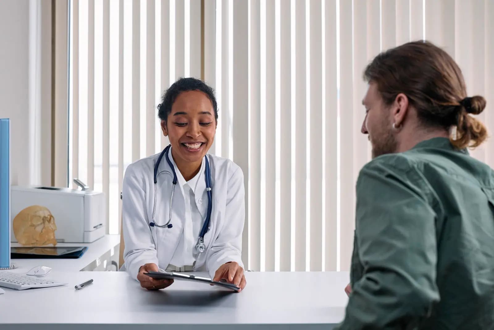 A physician speaking with a person across a clinic desk