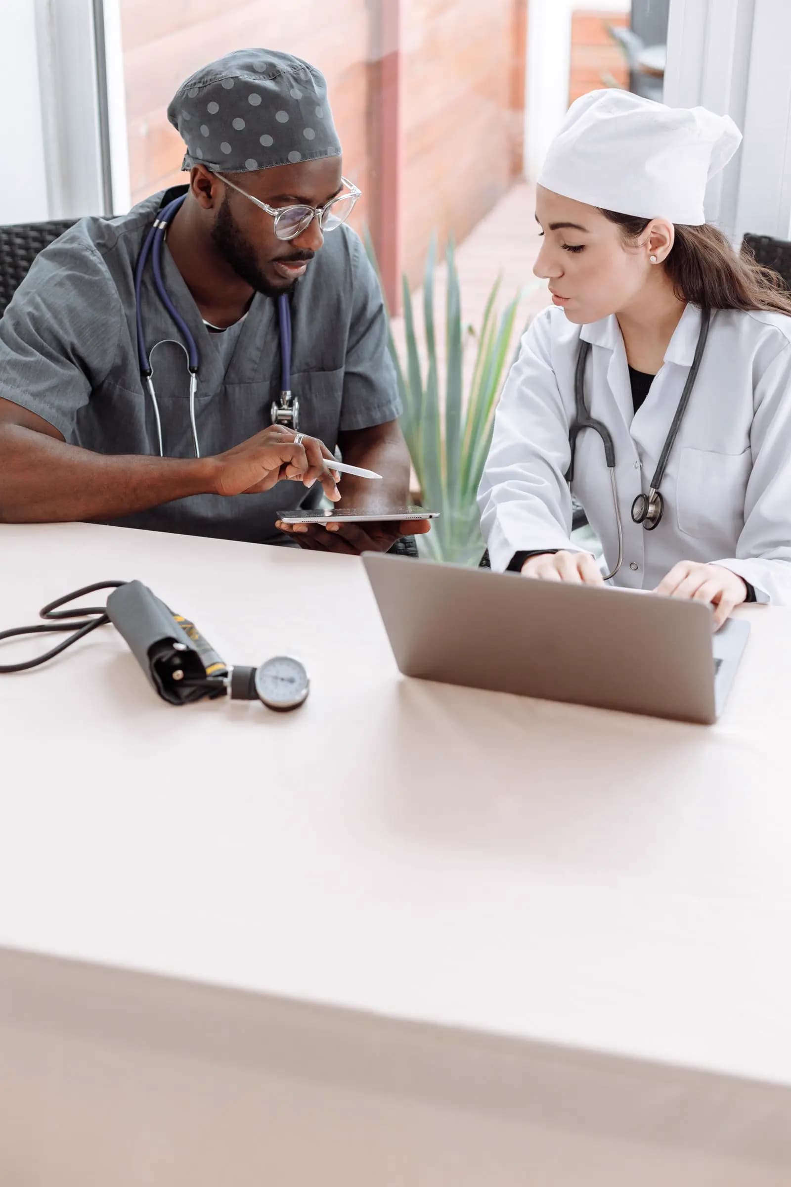 Two clinicians reviewing information together on a tablet and laptop