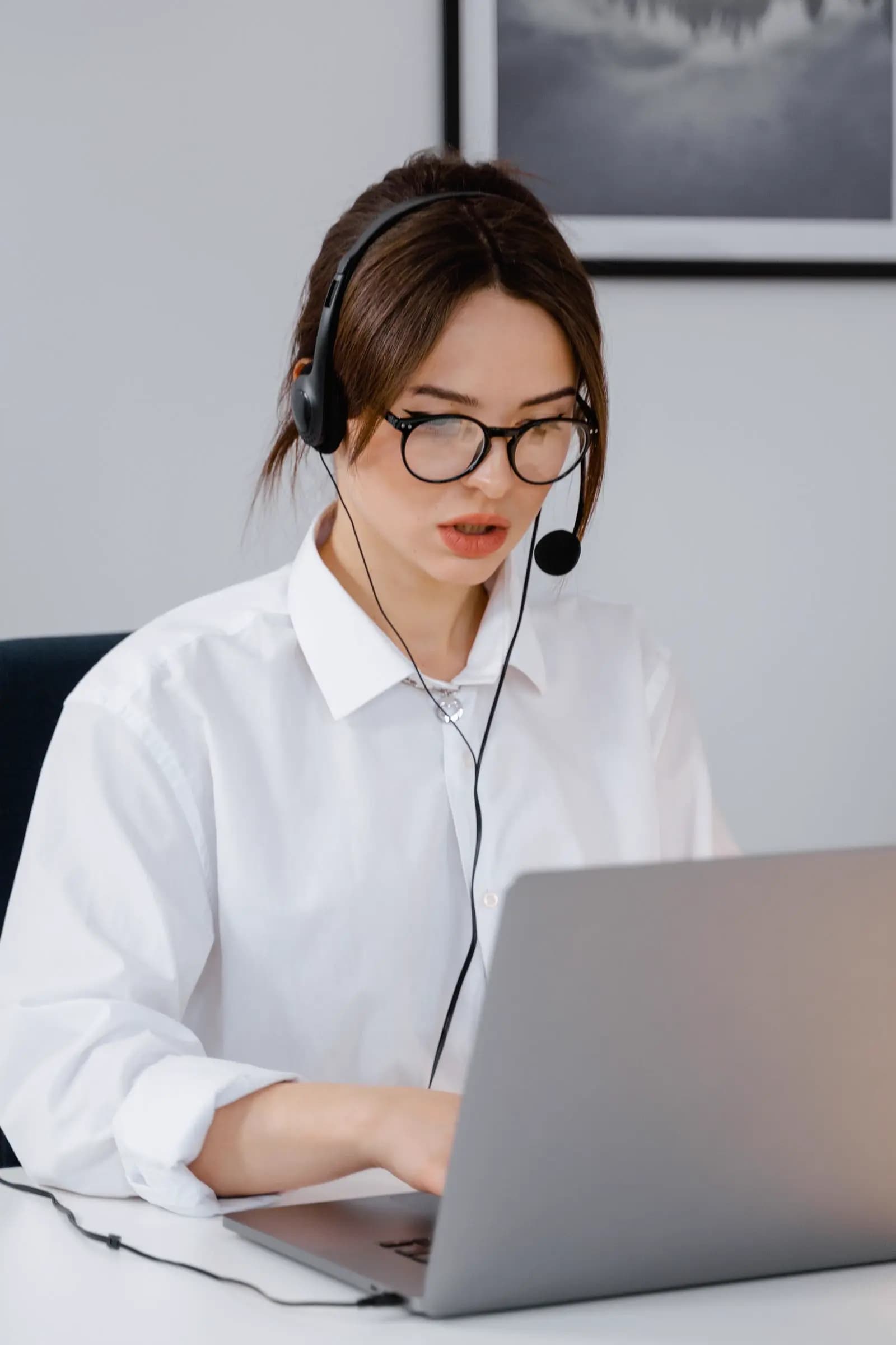 A support professional wearing a headset while working on a laptop